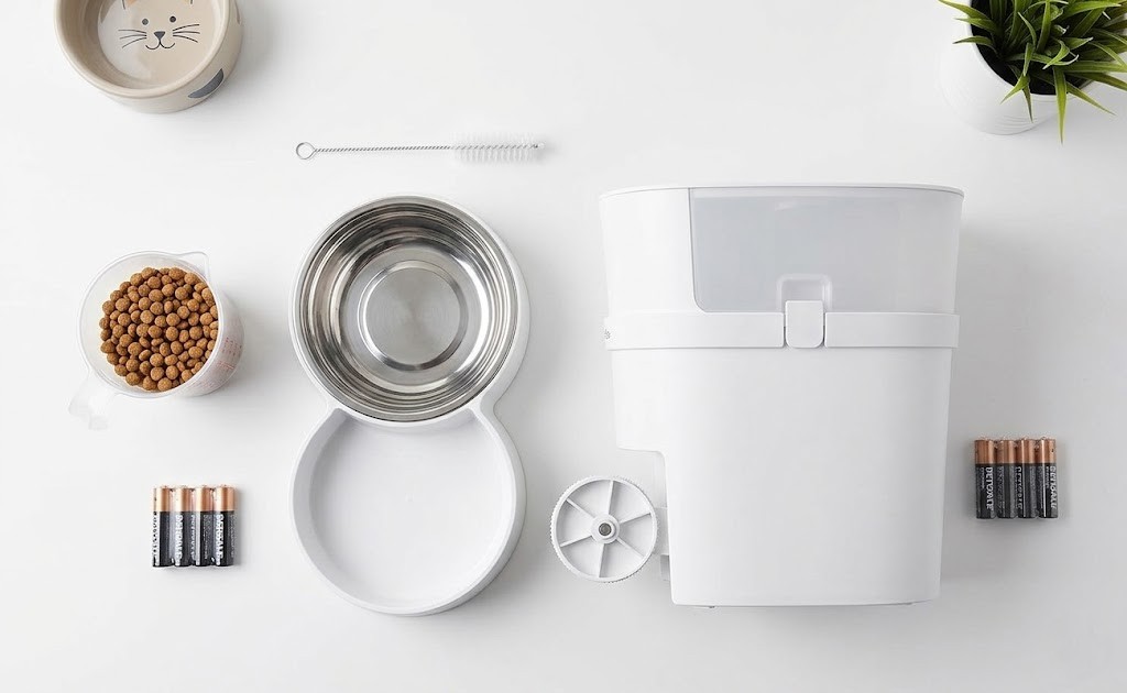 Pet feeder maintenance tools including cleaning brush, kibble measuring cup, and batteries